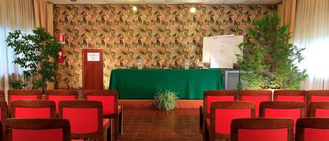 A conference room with red chairs, a green table, and a patterned wall.