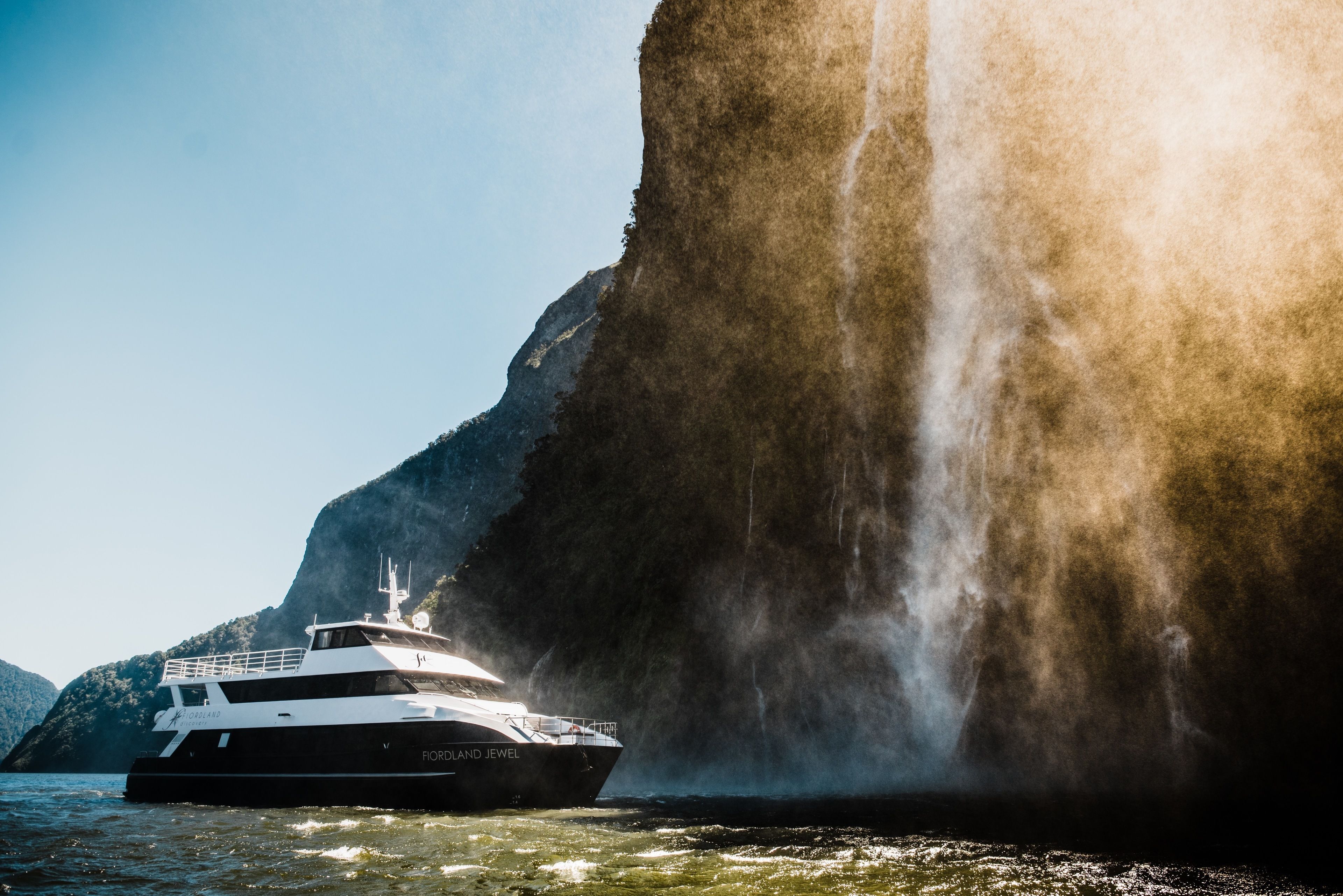 A boat named 'Florland Jewel' near a large waterfall.