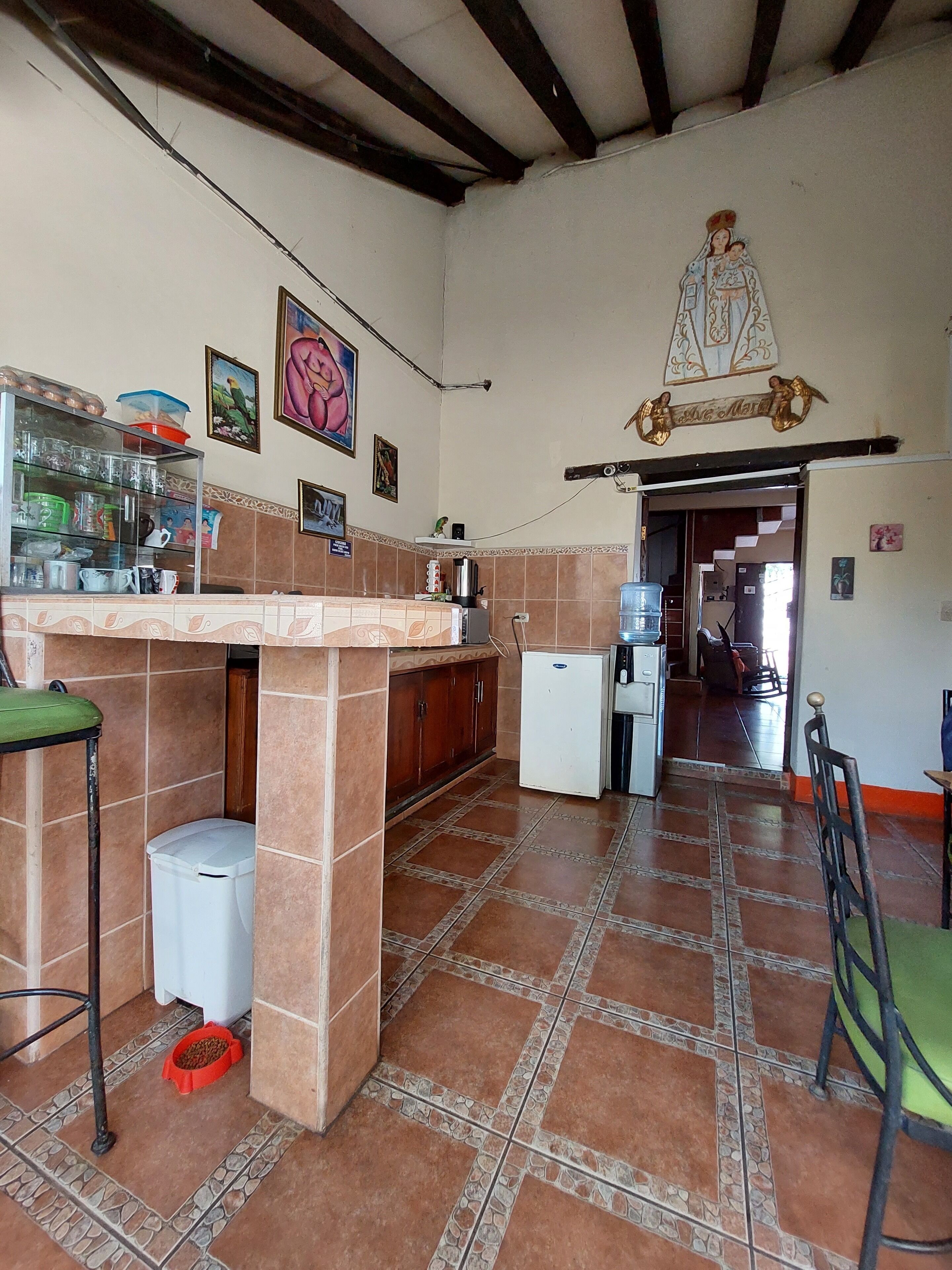 A kitchen with a tiled floor, a refrigerator, a sink, and a counter with various kitchen items.