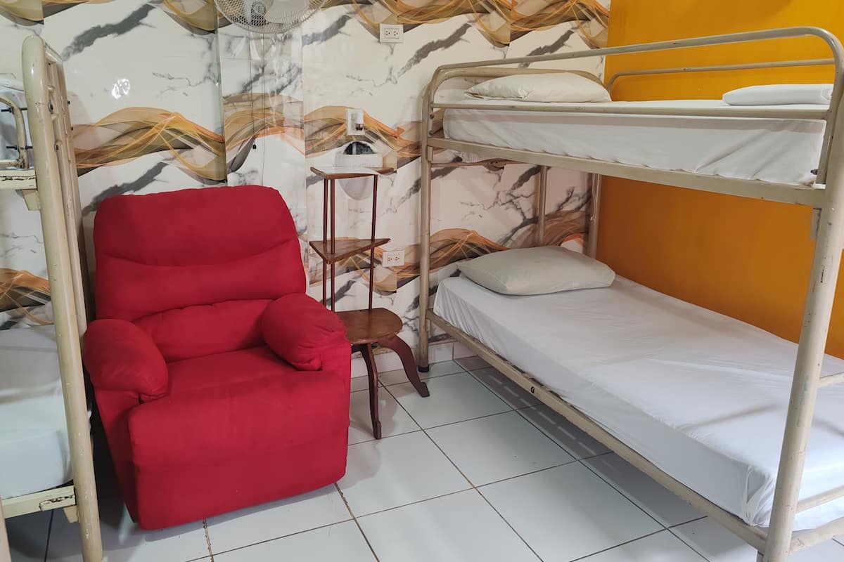 Ein Stockbett mit einem roten Stuhl und einem kleinen Tisch in einem Zimmer mit strukturiertem Wandpapier.
