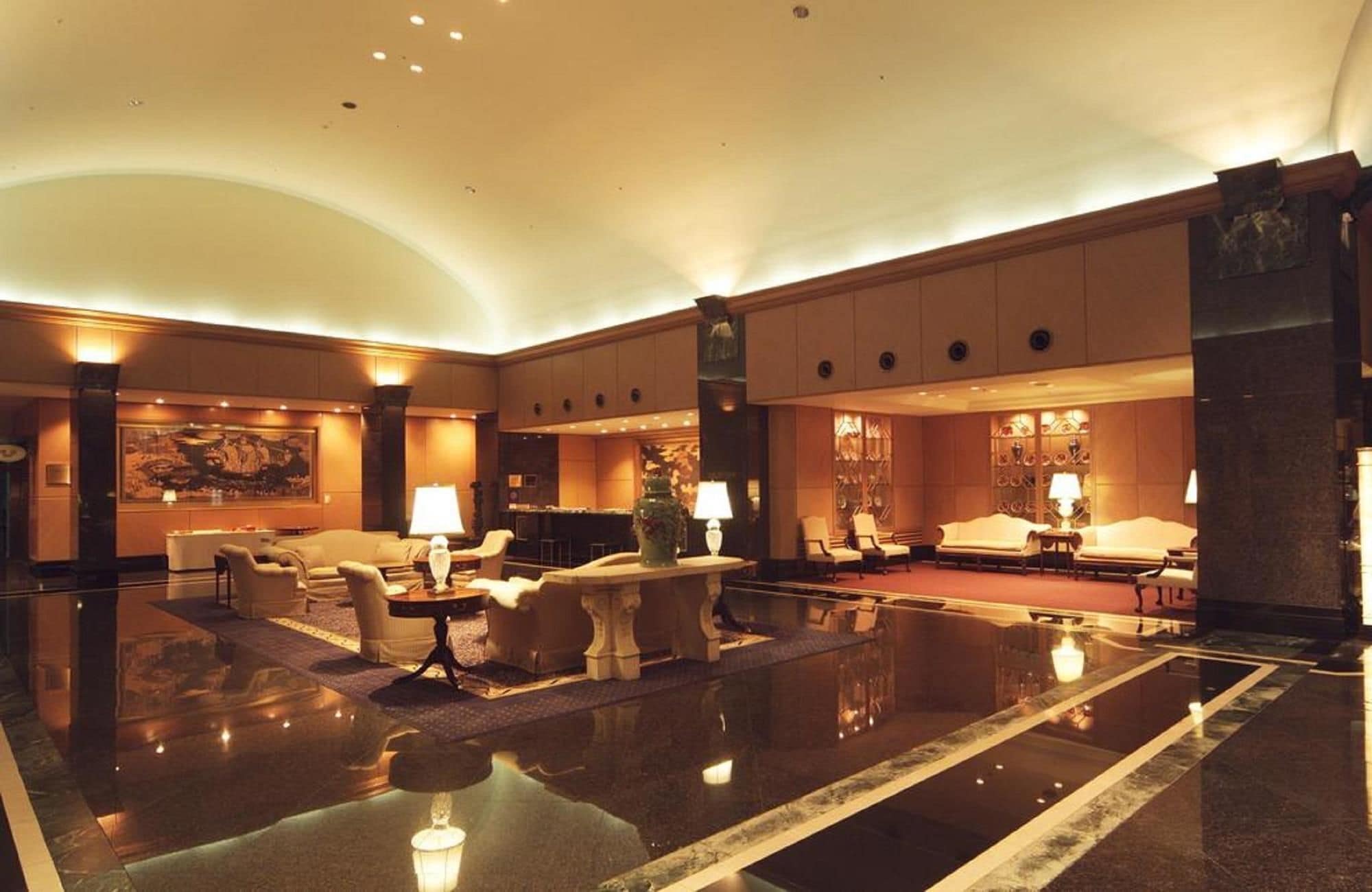 A spacious lobby with a polished floor, seating areas, and a bar.