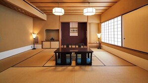 Une pièce de style japonais traditionnel, avec un sol recouvert de tatamis, une table basse et deux lampes suspendues.