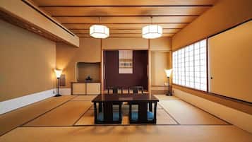 A traditional Japanese room with tatami flooring, a low table, and two hanging lamps.