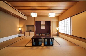 Una habitación japonesa tradicional con suelo de tatami, una mesa baja y dos lámparas colgantes.