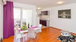 A modern apartment with a dining area, kitchen, and a cityscape view. - Apartments Mira (Dubrovnik)