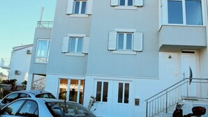 A multi-story residential building with white shutters, a visible entrance, and a staircase leading to the entrance. - Apartments Mira (Dubrovnik)