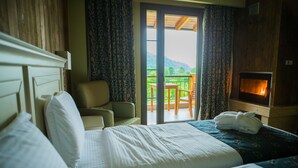 A hotel room with a bed, a chair, a table, and a fireplace.