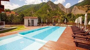 Una piscina cubierta, una piscina al aire libre, sombrillas, tumbonas