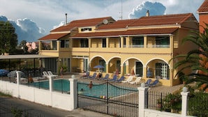 Un edificio de dos pisos con piscina, zona de estar exterior y área cercada.