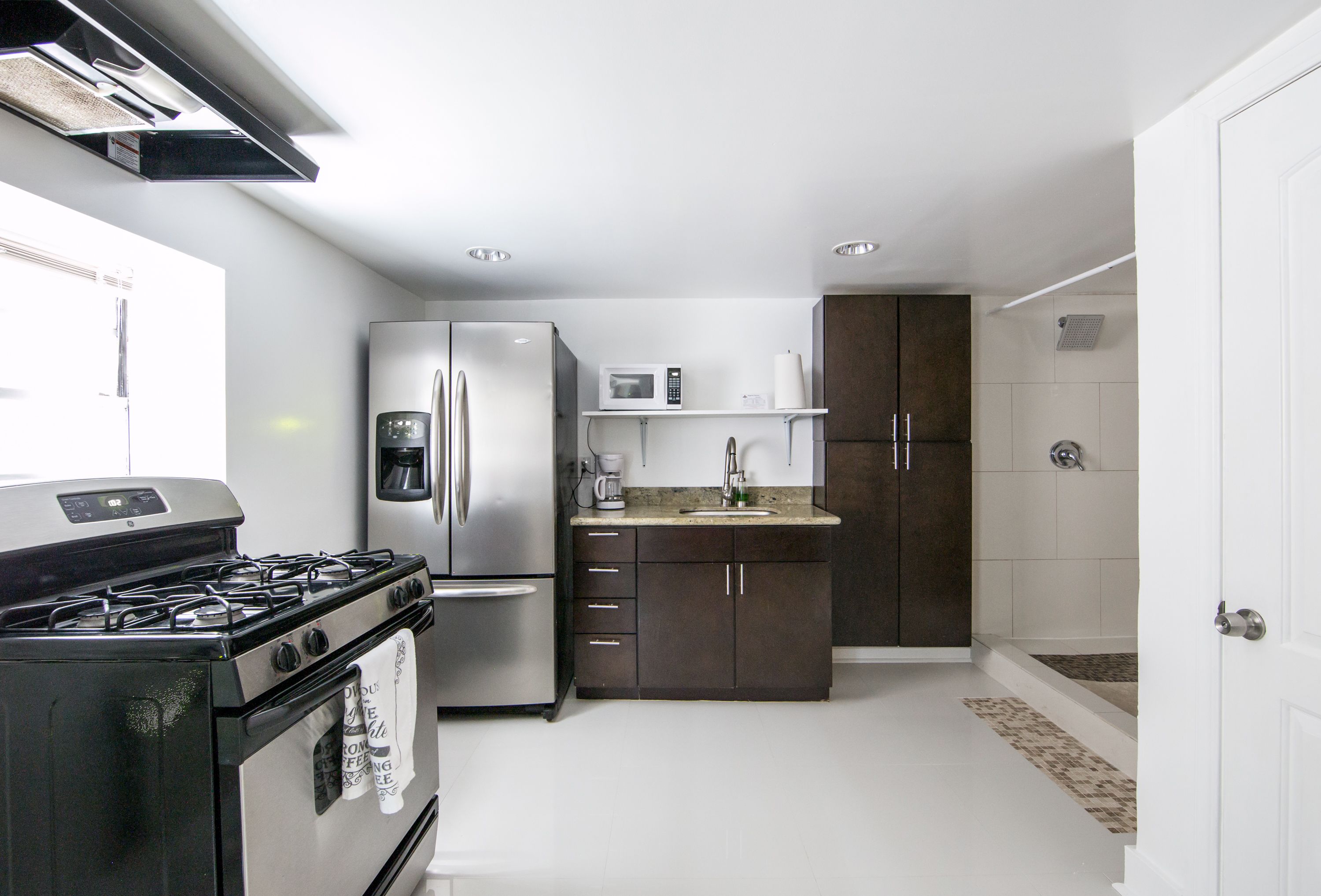 Una cocina moderna con estufa, refrigerador, microondas y armarios oscuros.