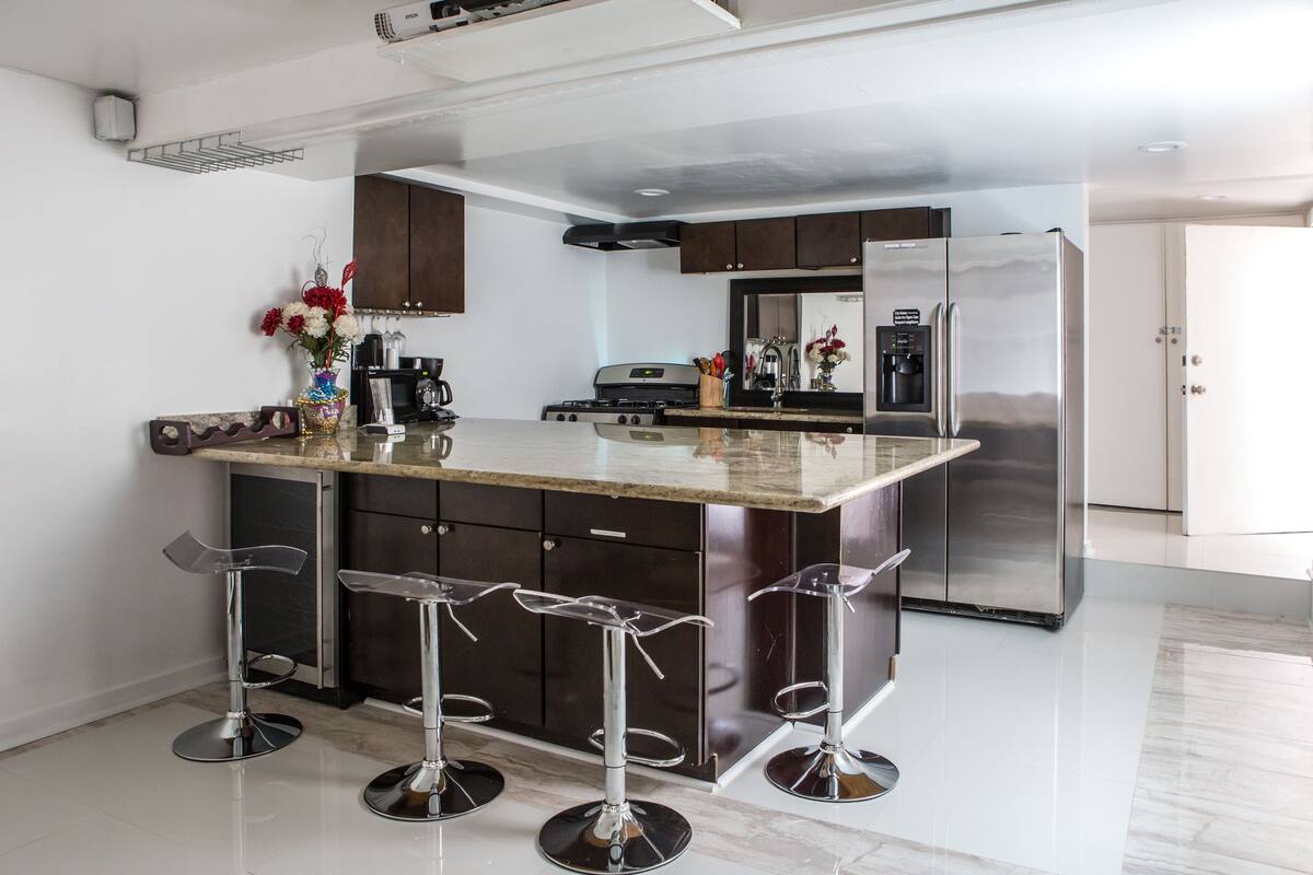 A modern kitchen with a central island, stainless steel appliances, and bar stools.