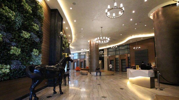 Un hall d’entrée avec un comptoir de réception, une statue de cheval et un mur végétal.