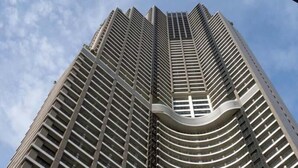 Un immeuble de grande hauteur doté d’une architecture moderne, caractérisé par une section centrale incurvée et une série de balcons disposés en réseau.