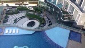 Un bâtiment moderne doté d’une grande piscine à la forme originale, agrémentée d’un motif en forme de couronne, et entouré d’espaces de détente et d’un jardin paysager.
