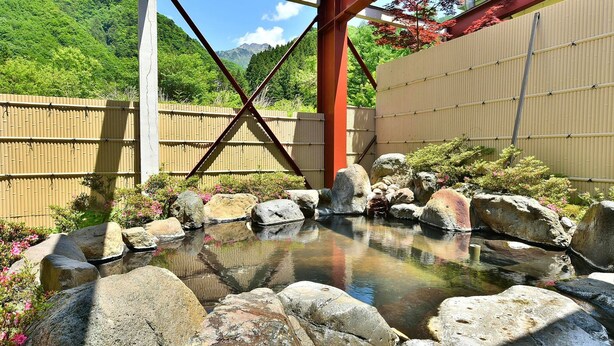 A traditional Japanese garden with a koi pond, rocks, and bamboo fences. - Tajimakan (Takayama)