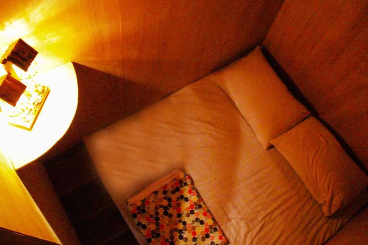 Een hotelkamer met een bed, kussens, een nachtkastje en een lamp.