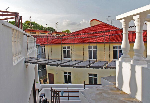 Un edificio residencial con techo de tejas rojas, balcones y fachada blanca.