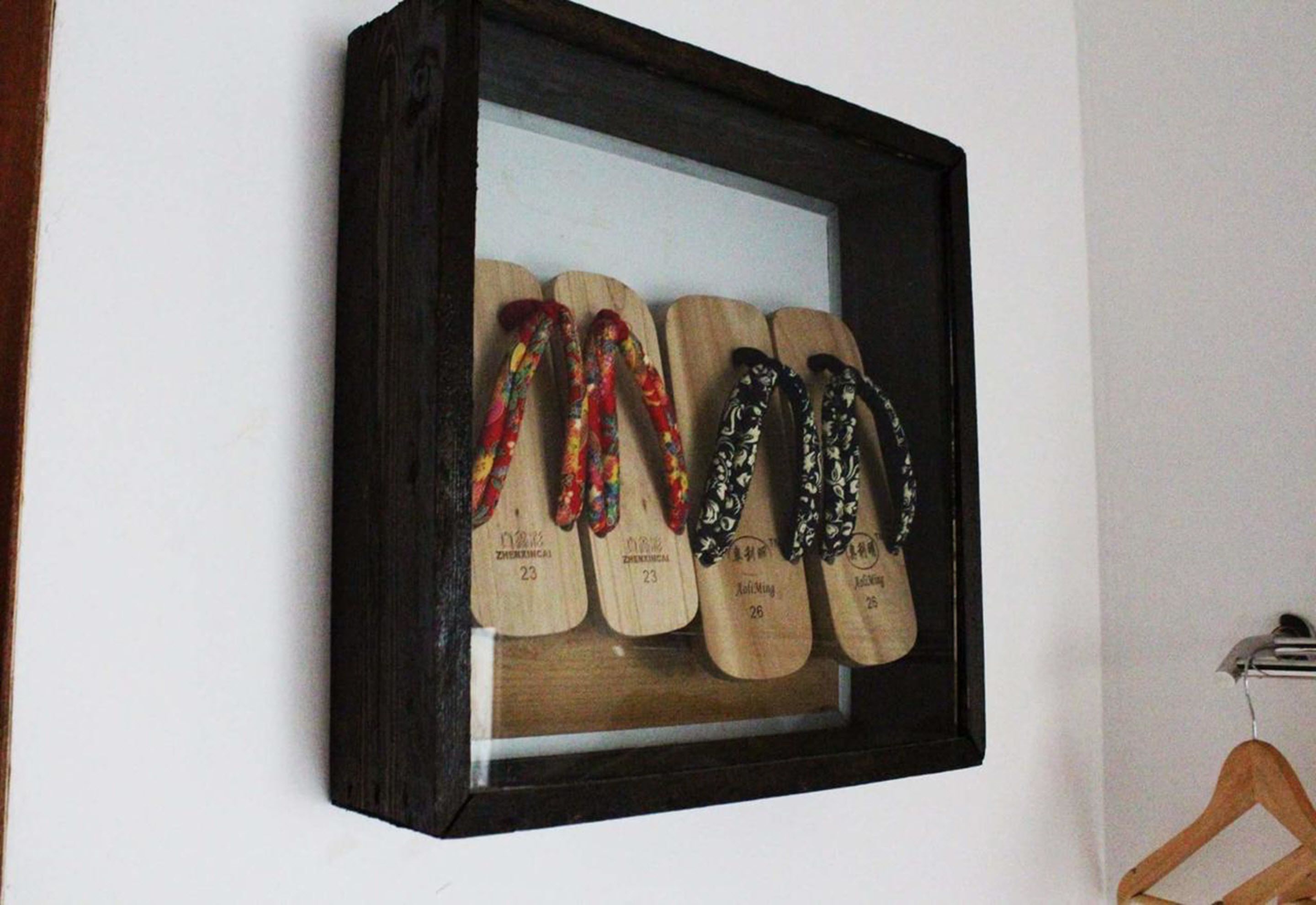 A framed display of wooden shoes with various designs and numbers.