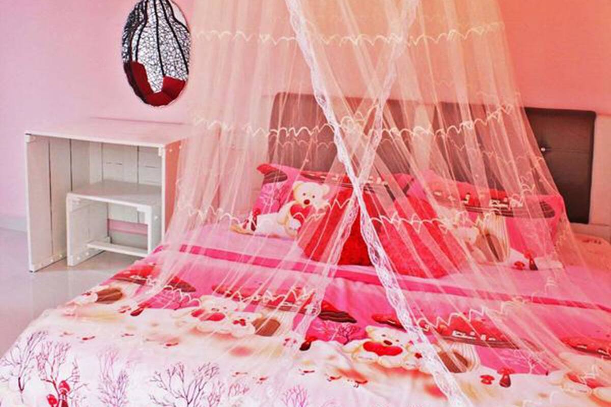 Een slaapkamer in roze tinten met een hemelbed, een kroonluchter en een wanddecoratie.