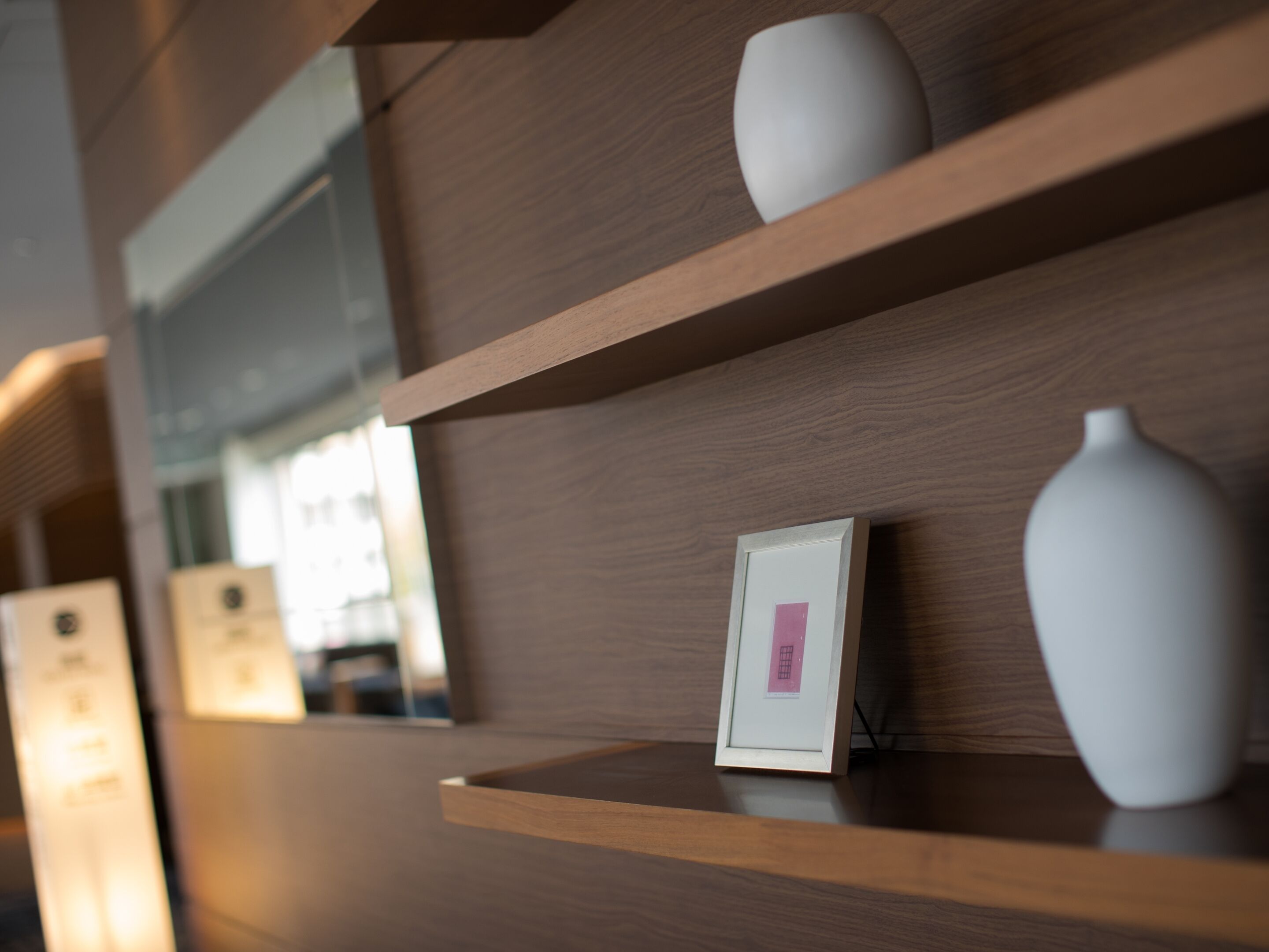 A wooden wall with shelves displaying vases and framed pictures.