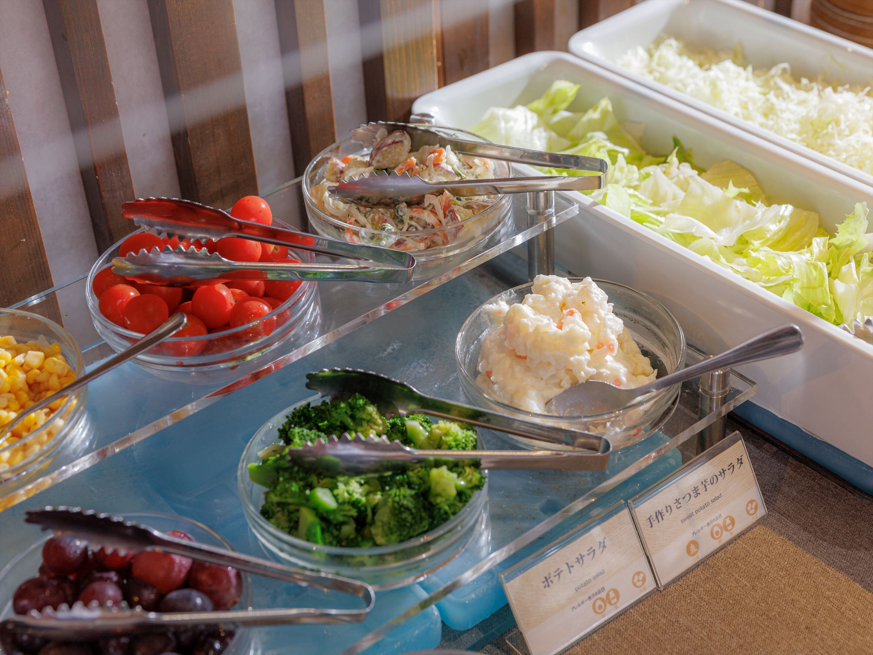 A buffet with various dishes including tomatoes, broccoli, and a potato salad.