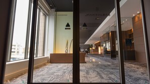 Un hall d’hôtel comprenant un comptoir d’accueil, un espace salon et une vue sur la rue.