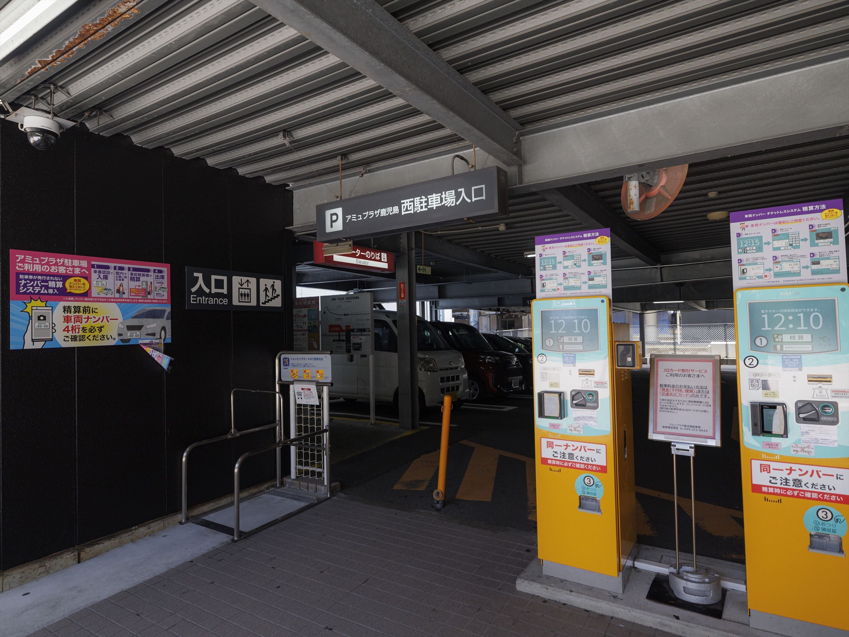 A parking garage entrance with a sign indicating the entrance and an elevator.