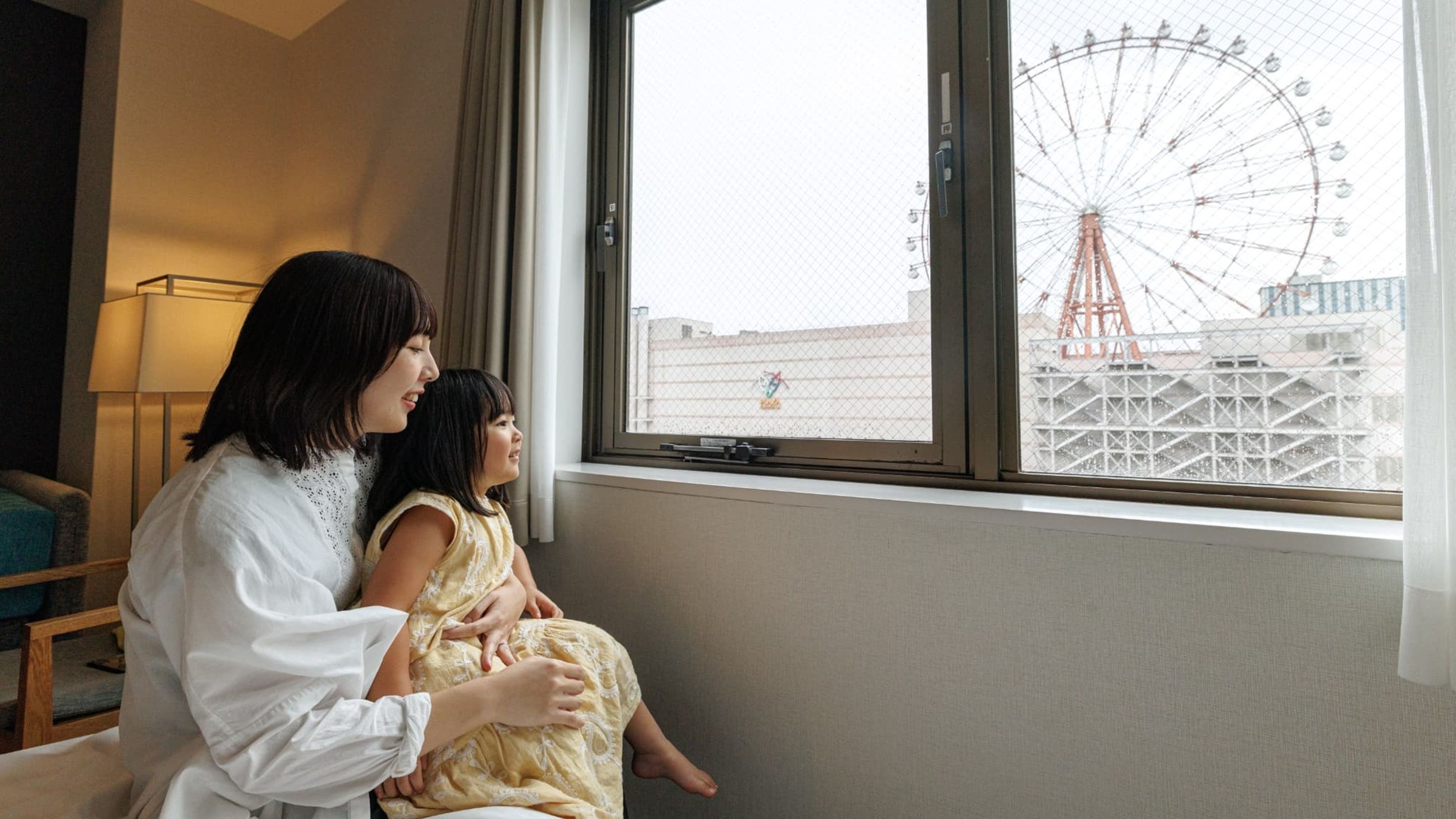 A room with a large window overlooking a Ferris wheel.