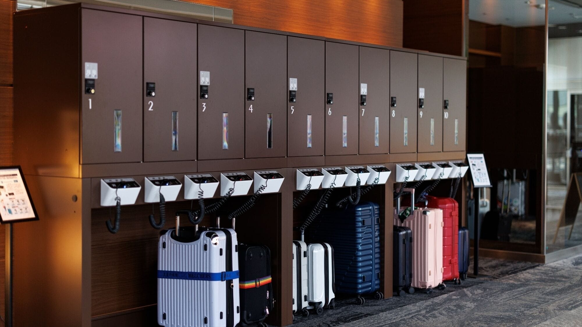 A row of luggage storage lockers with numbered compartments and a signboard.