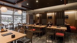 Un restaurant avec des tables et des chaises en bois, de grandes fenêtres et un plafond à carreaux.