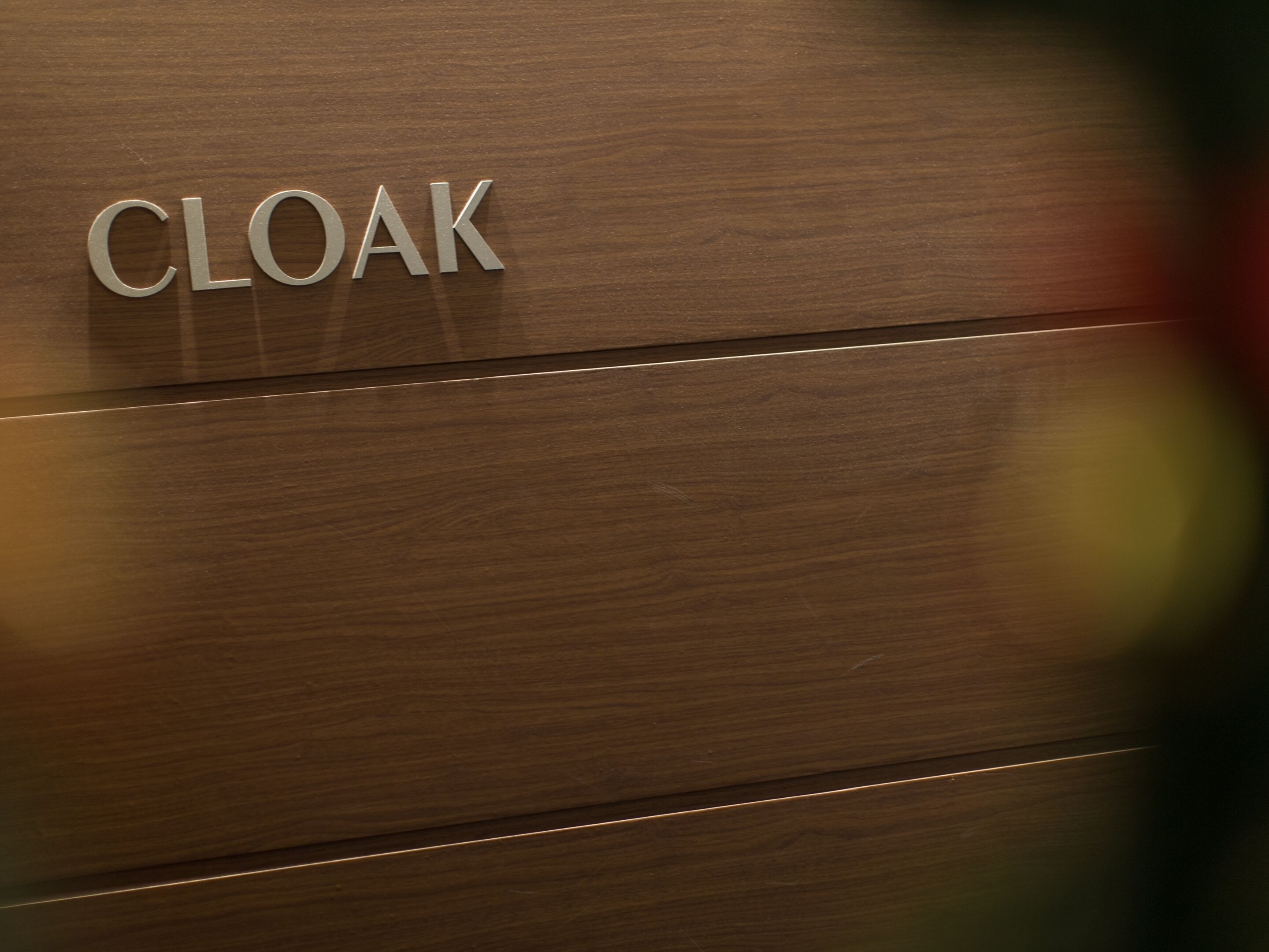 Un panel de madera con la palabra 'CLOAK' grabada.