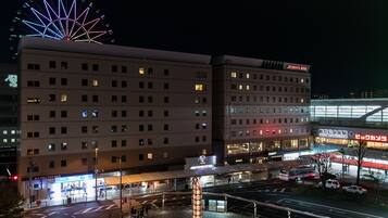 Um hotel de vários andares com design moderno, destacando uma entrada imponente com área coberta e estacionamento visível.