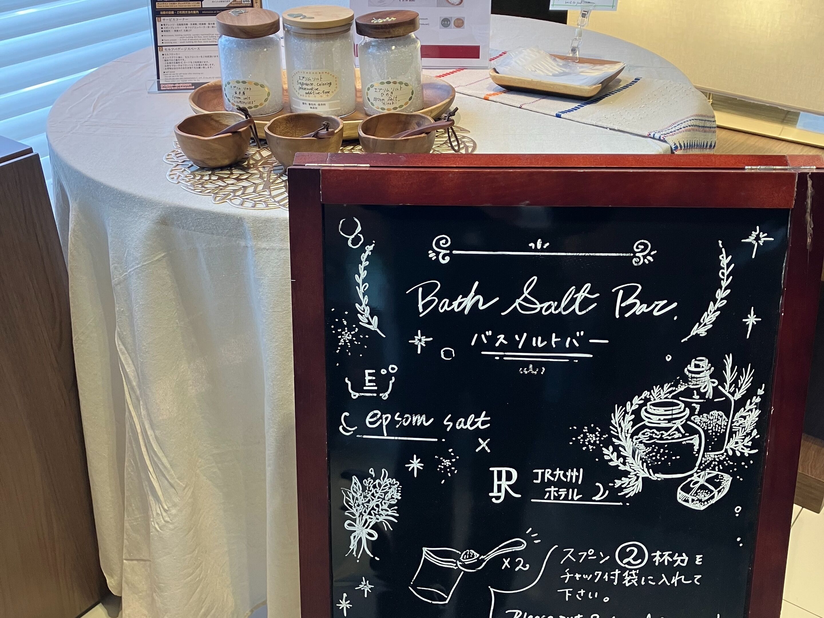 A table with salt jars and wooden bowls, a chalkboard menu with Japanese text, and a wooden counter.