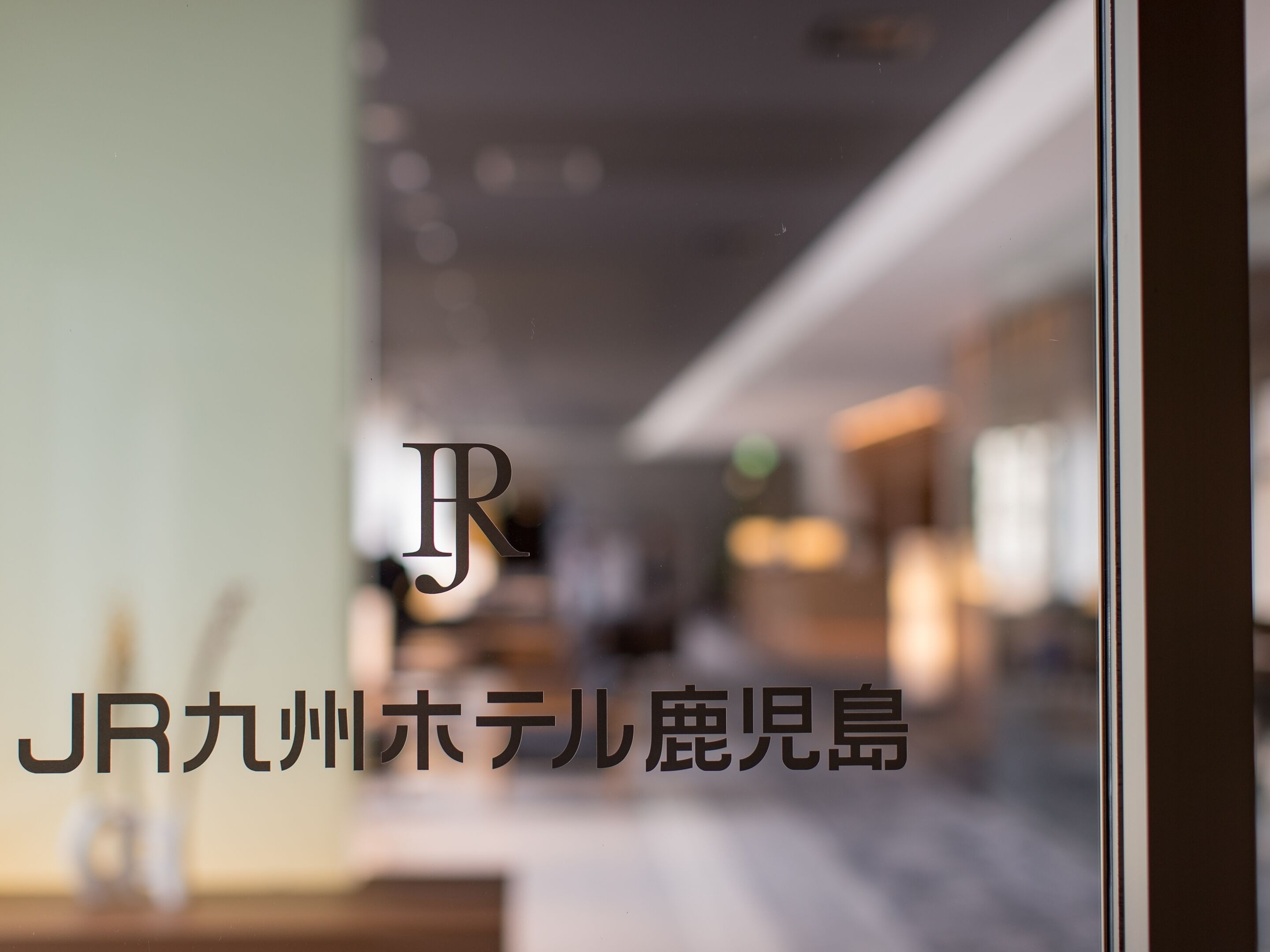 A blurred interior view of a hotel with a visible logo and Japanese text.