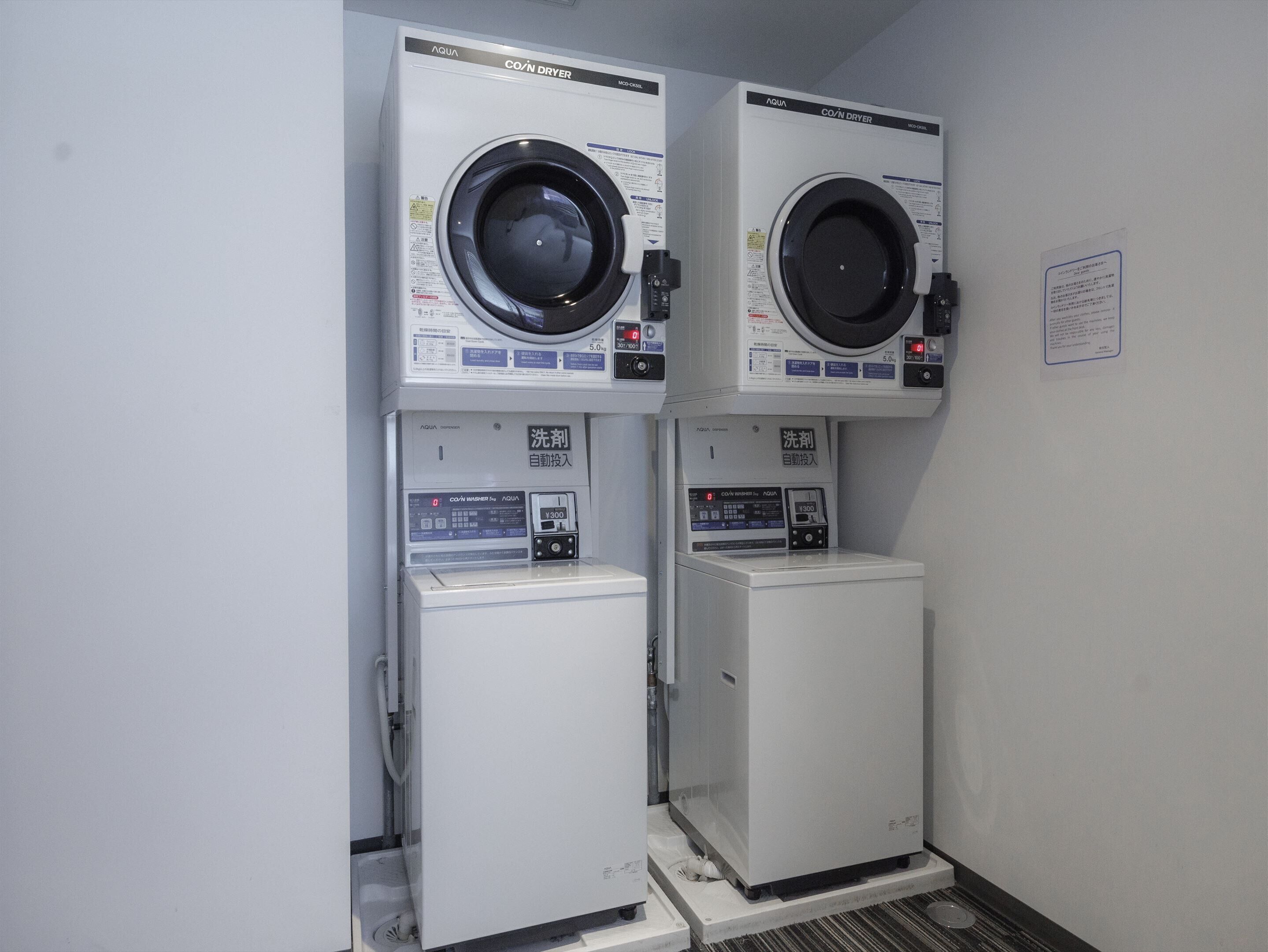 Two stacked laundry machines with control panels and a small sink below.