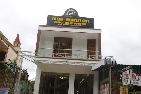 A building with a sign reading "Mini Mansion" and "Expect the Unexpected."