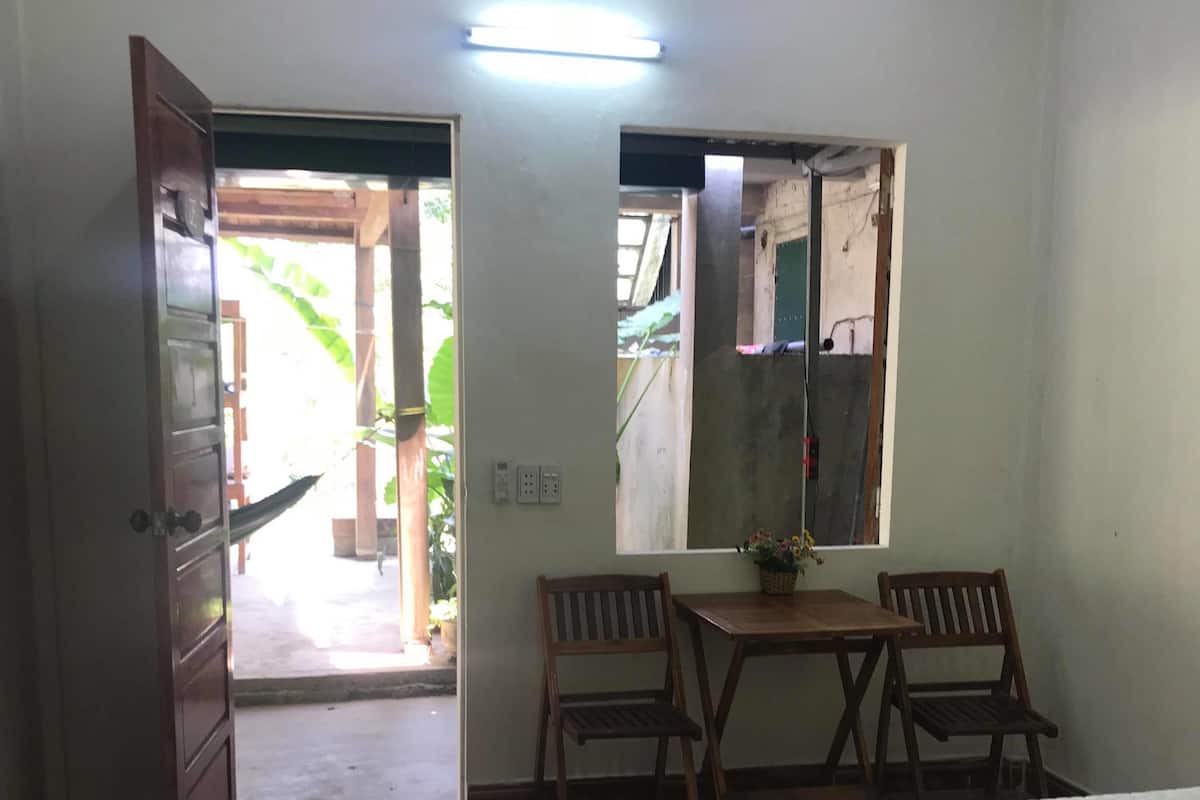 A room with a bed, a desk with two chairs, a mirror, and a door leading outside.