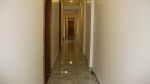 A long, narrow hallway with a shiny, reflective floor and a wooden door at the end.