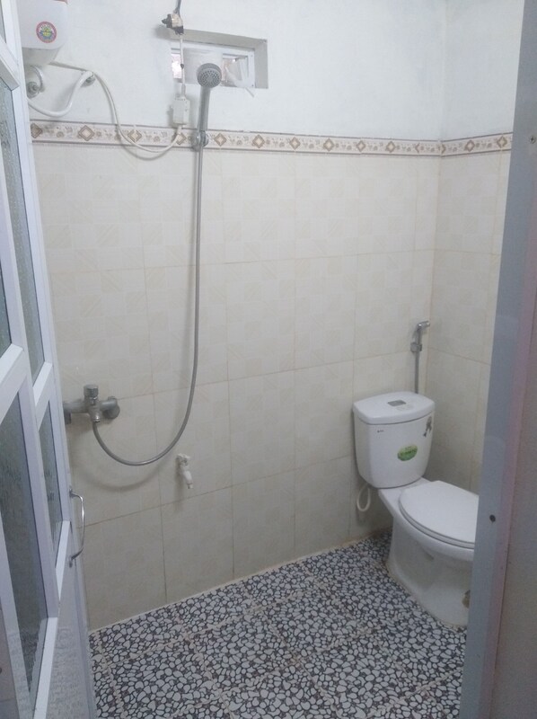 A small bathroom with a toilet, a shower, and a tiled floor.