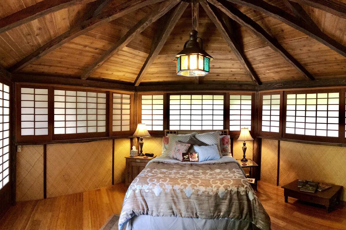A traditional Japanese-style bedroom with a wooden ceiling, tatami flooring, and shoji screens.