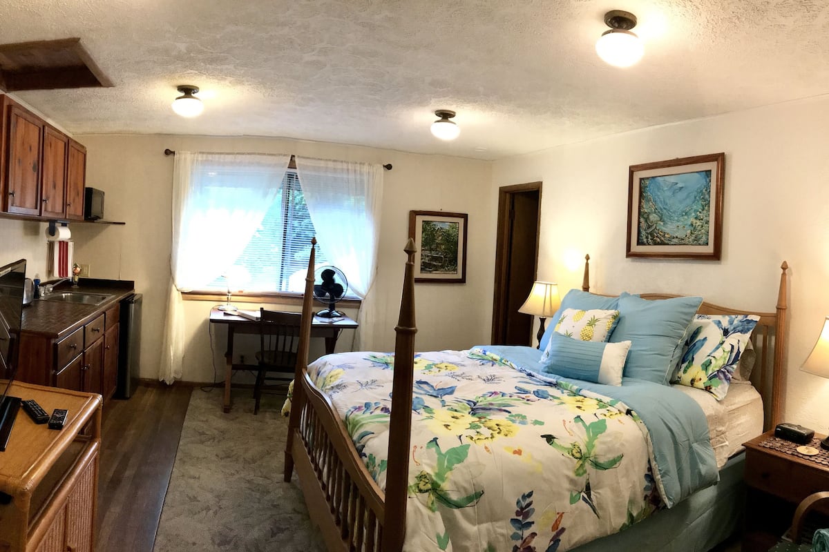 A bedroom with a bed, desk, and computer setup.