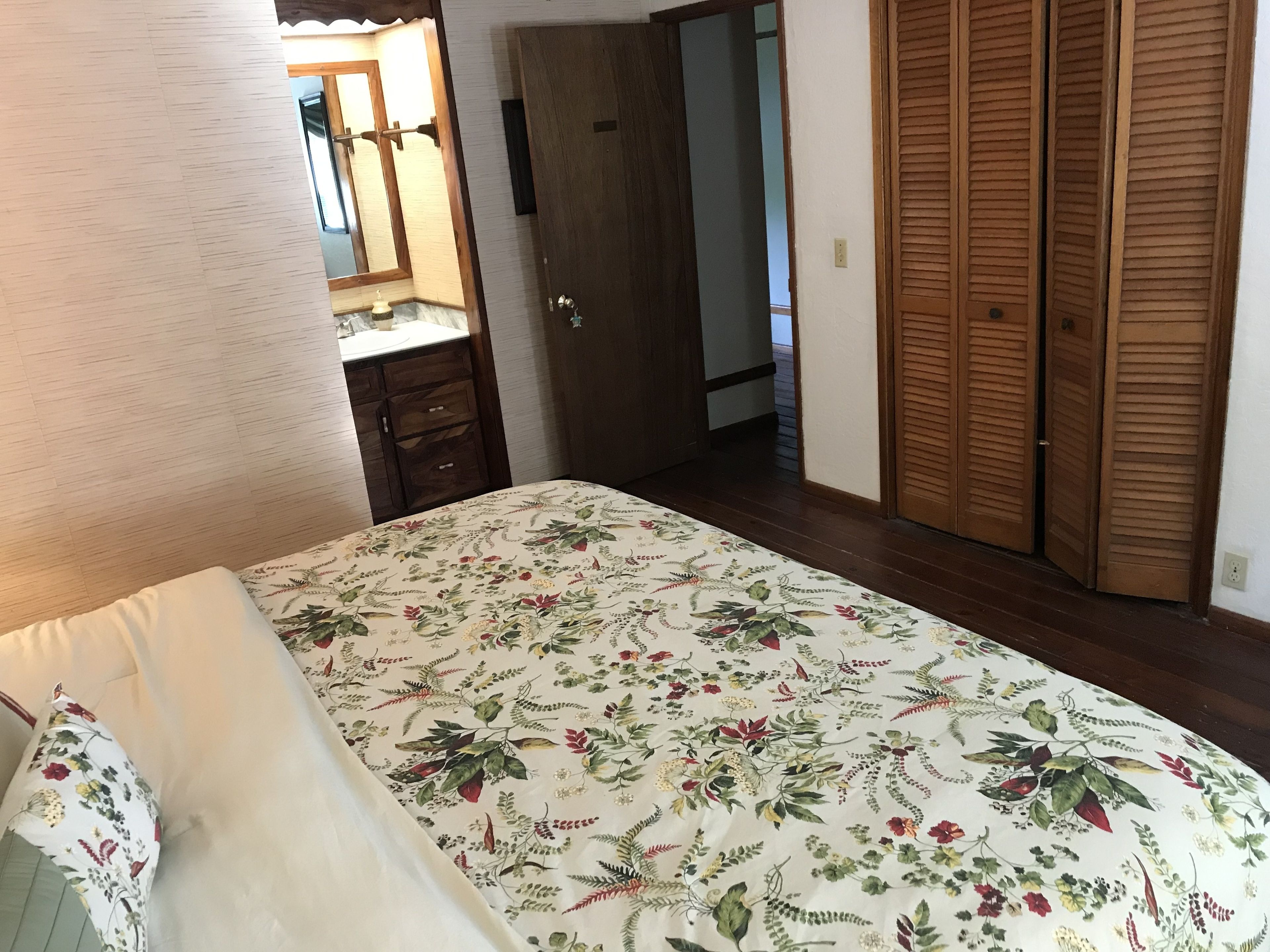 Une chambre à coucher comprenant un lit, une commode, un miroir et une armoire en bois.