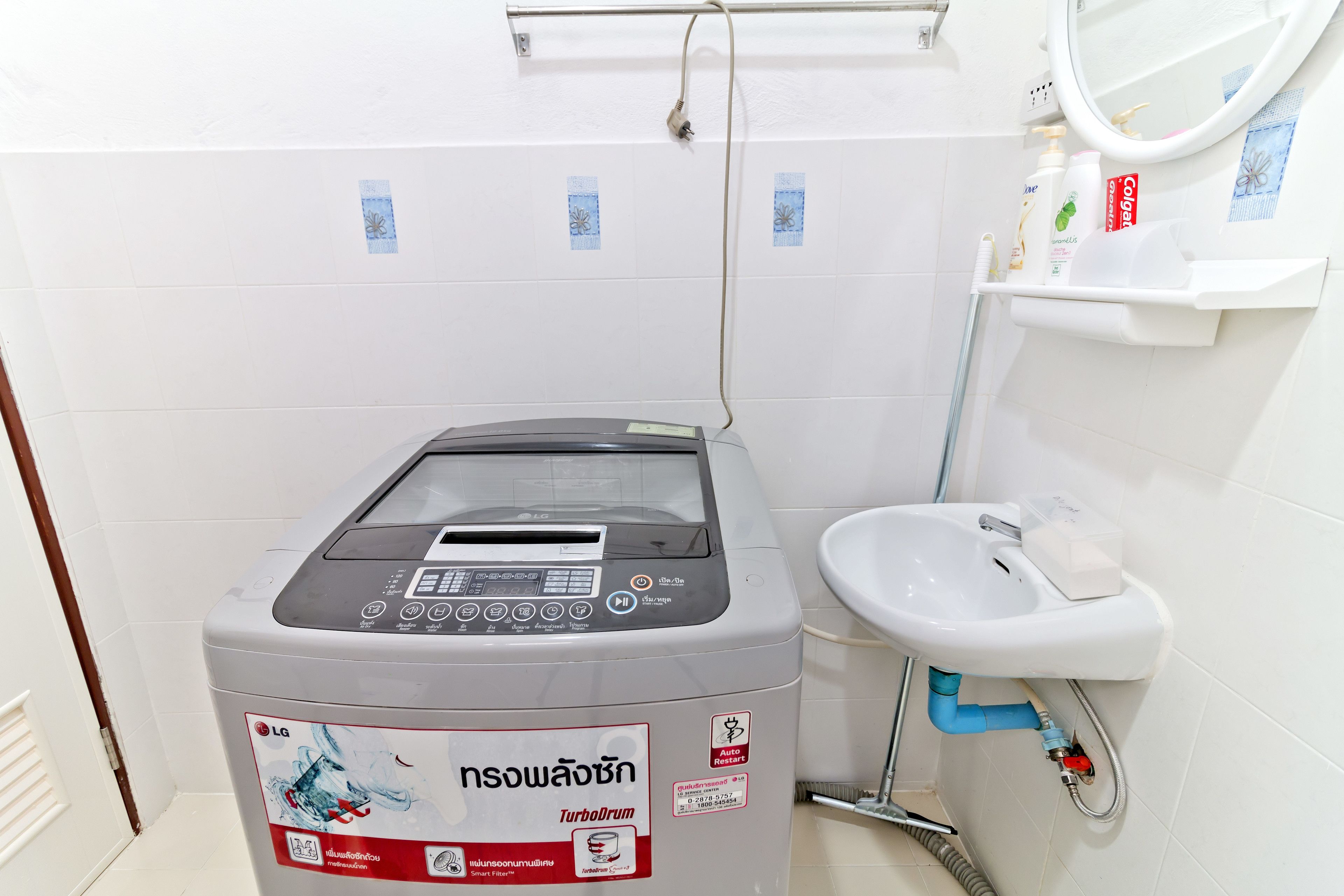 A compact washer and dryer unit with a control panel, a white sink with a soap dispenser, and a mirror above the sink.