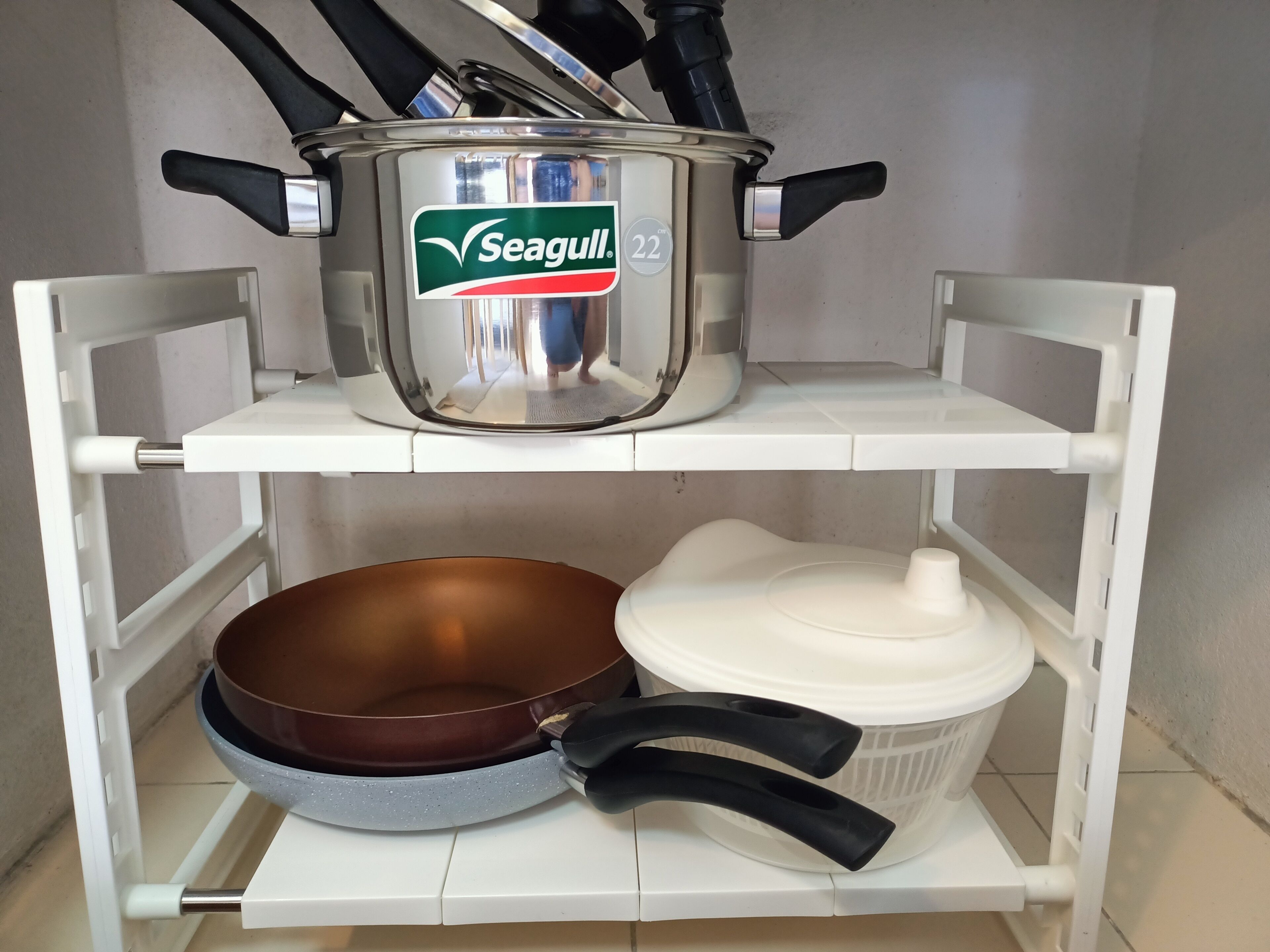 Una repisa de cocina con una olla Seagull, una sartén marrón y un recipiente blanco.