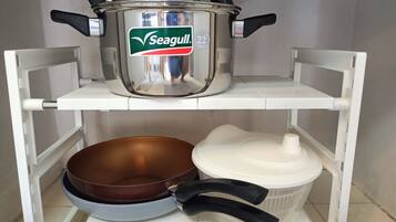 Una repisa de cocina con una olla Seagull, una sartén marrón y un recipiente blanco.
