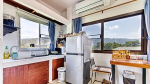 Cocina compacta con refrigerador, pileta y ventana con vista a un paisaje montañoso.