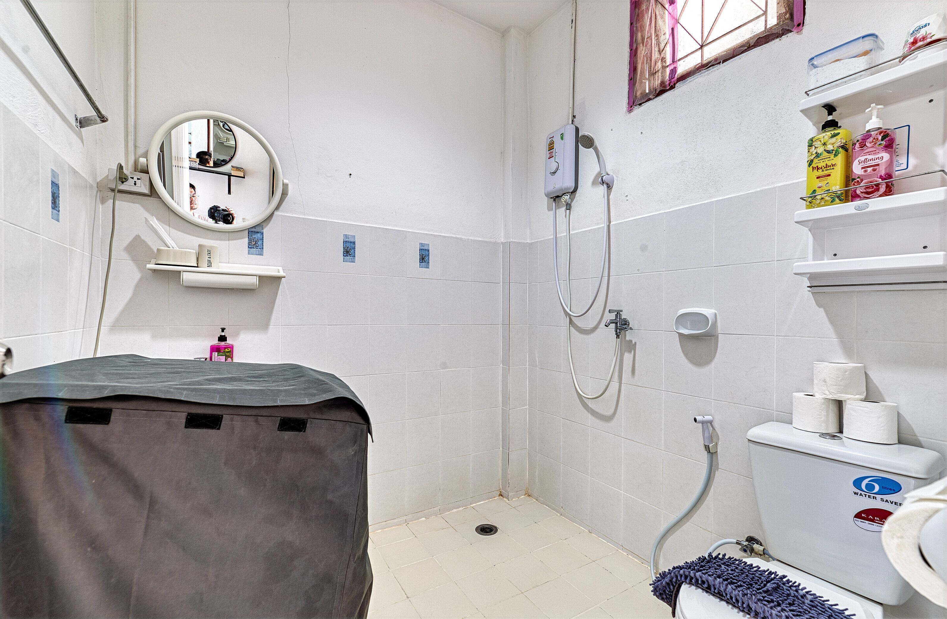 Un bagno piccolo e pulito con doccia, wc e lavandino. Sui ripiani ci sono articoli da toilette e uno specchio sopra il lavandino.