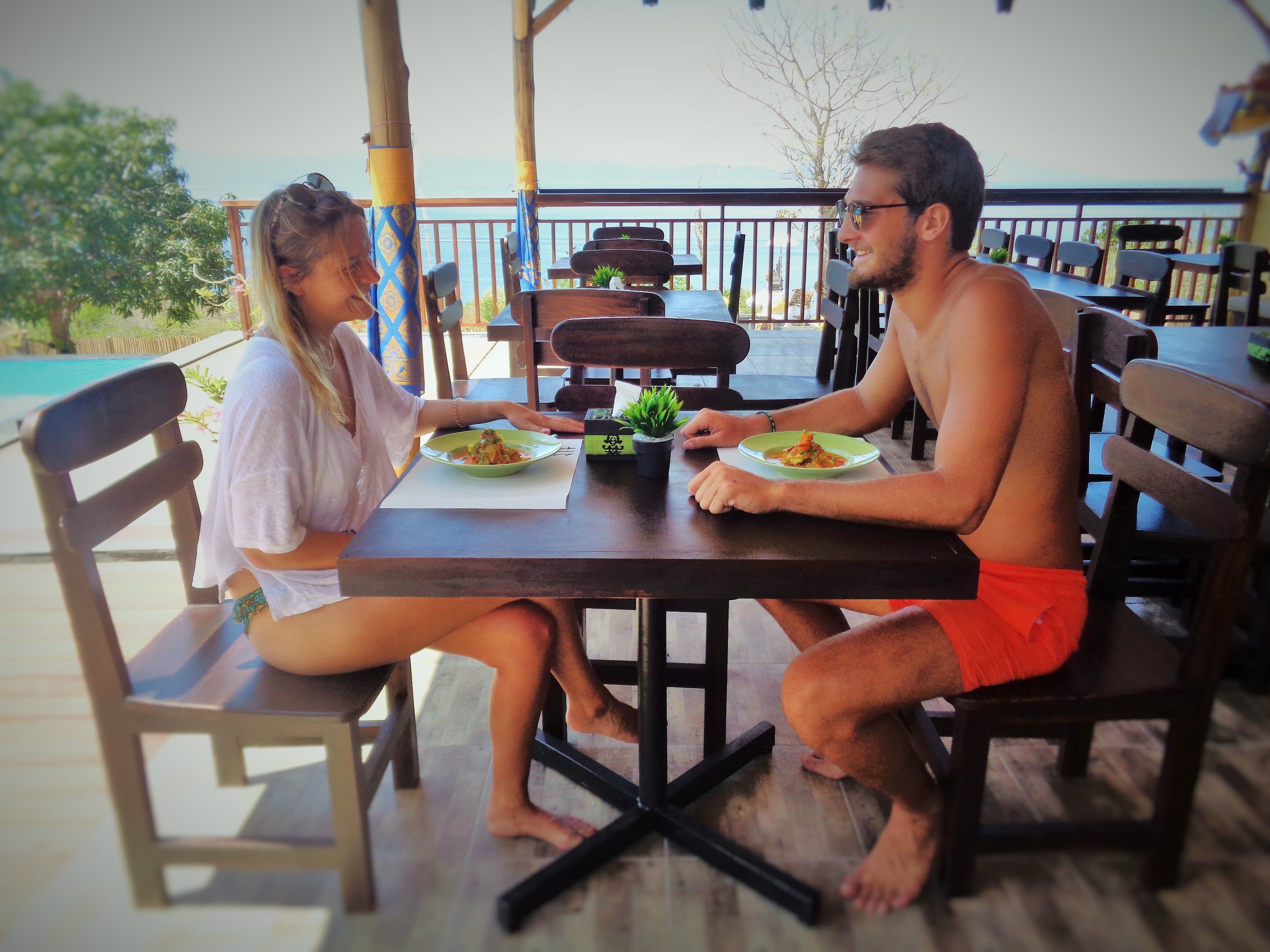 A couple dining at an outdoor table with a view of the sea.