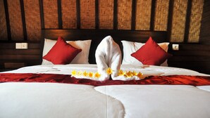 A neatly made bed with white linens, red pillows, and a red blanket. - Bataran Garden Cottage (Penida Island)