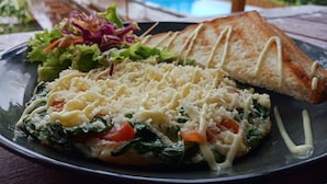 A plate of food with a salad, a slice of toast, and a vegetable dish. - Bataran Garden Cottage (Penida Island)